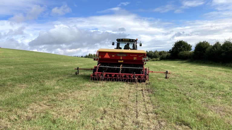 Rear view of tractor in farmer's field in autumn with seed drilling equipment in use